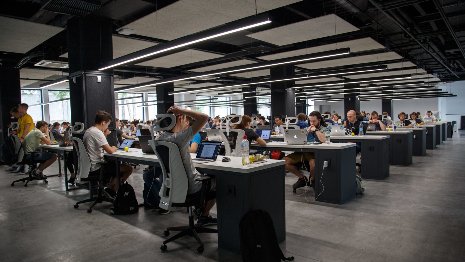 Grand open space de bureau avec de nombreux employés travaillant sur des ordinateurs portables