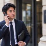 Commissaire de justice devant son office, au téléphone